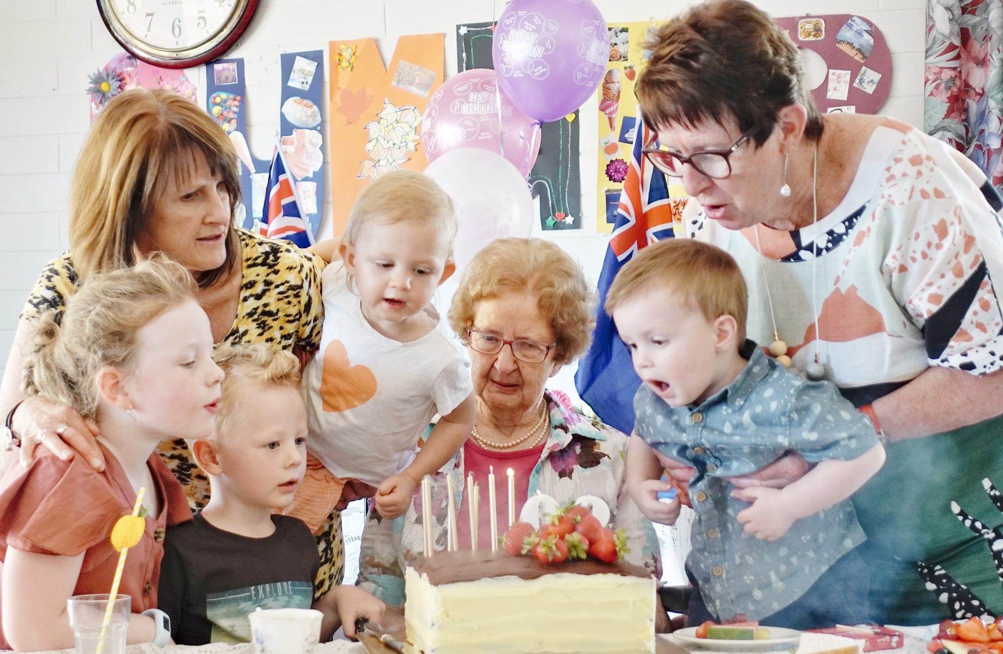 Daughters Helen (left), Robyn and some great grandchildren help Rita Trollop blow out the candles on her 90th birthday cake.