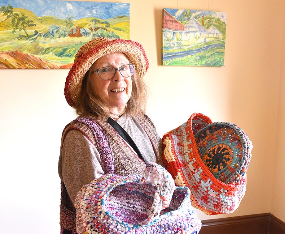 Artist, Kate Giakimis is pictured with some of her uniquely crafted baskets made from bread bags and rags, with, in the background, a selection of her acrylic paintings. Kate said it takes around 2 kilograms of rags to create one of the larger baskets.