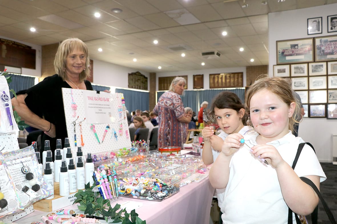 Piper Kemp and Heidie Kilroy make beads at Ronnie Cozens bead bar in the market stall..