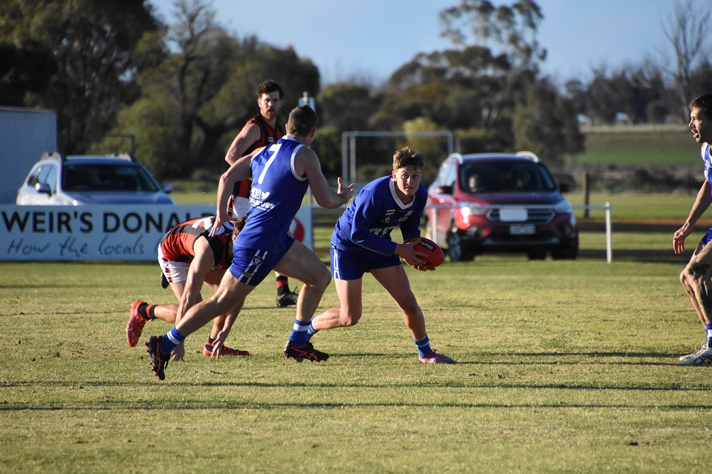 Donald’s Noah Berry avoids the tackle of Wedderburn’s Corey Lowry. Donald’s Ross Young runs past for the handball and Wedderburn’s Mackenzie Smith is in the background.