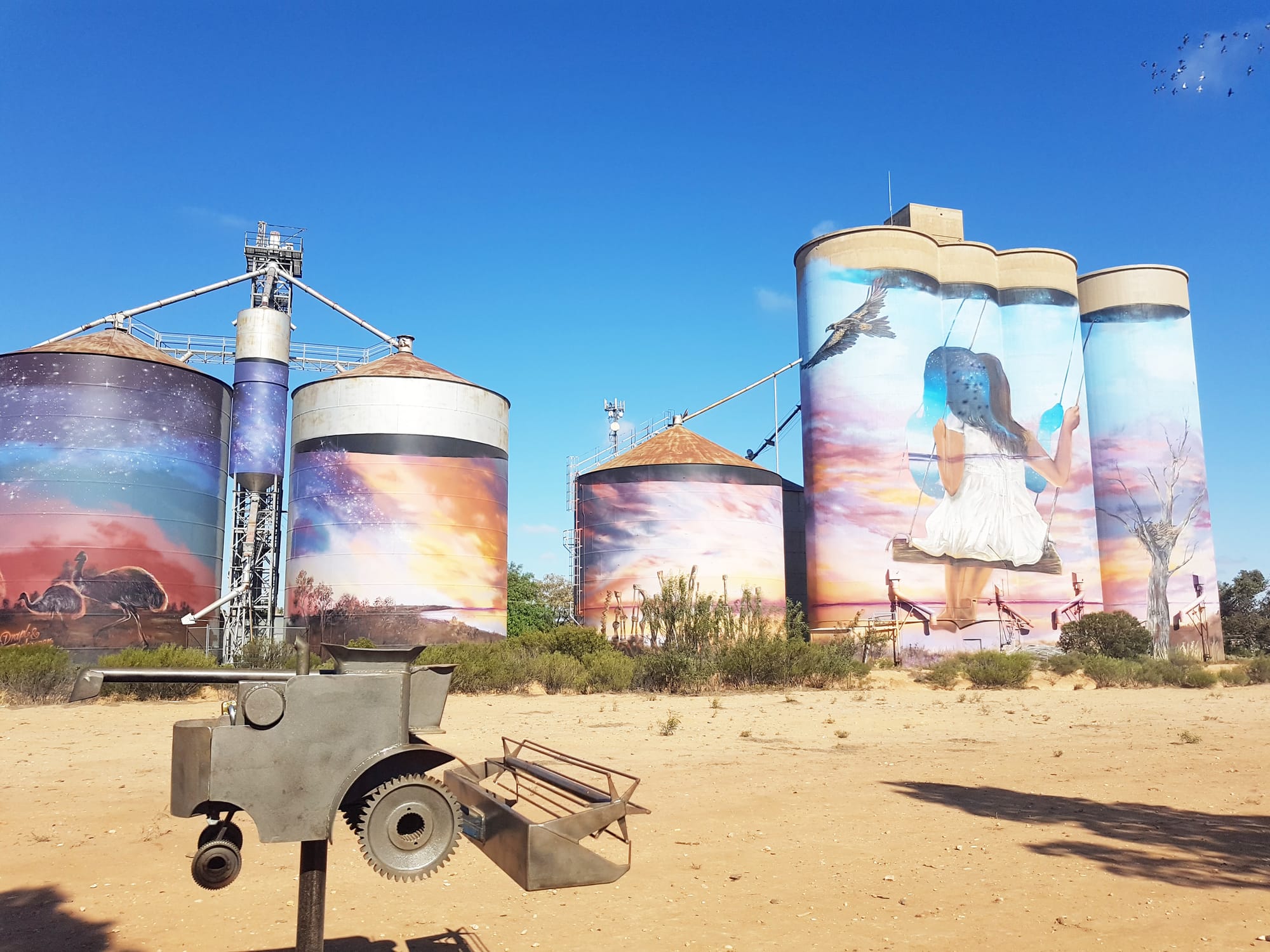 Sea Lake Silo Art is difficult to capture in one photo with the vast sky dominating the background, in the foreground is a little piece of art in itself. A steel header that doubles as a donation box (every little bit helps).