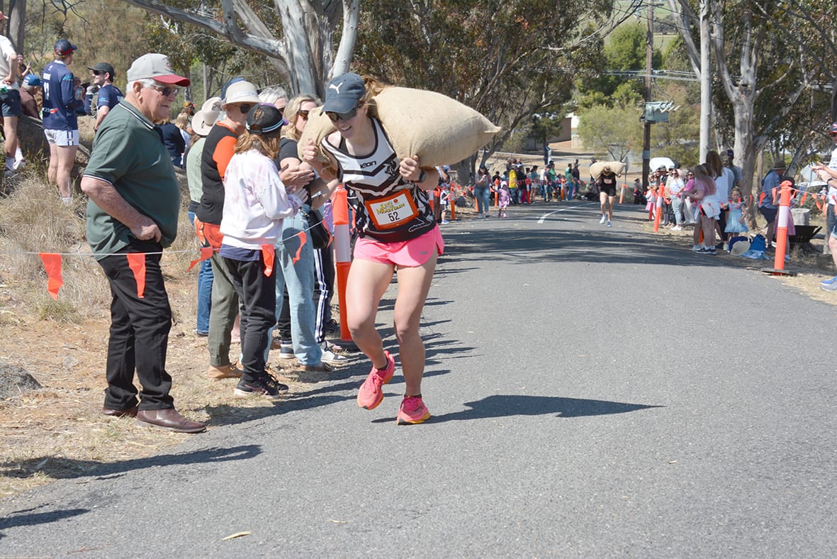 Carly Isaac approaches the last bend on the course during the Queen of the Mountain race, and lifted by the support of her cheer squad, even finds the strength to smile.